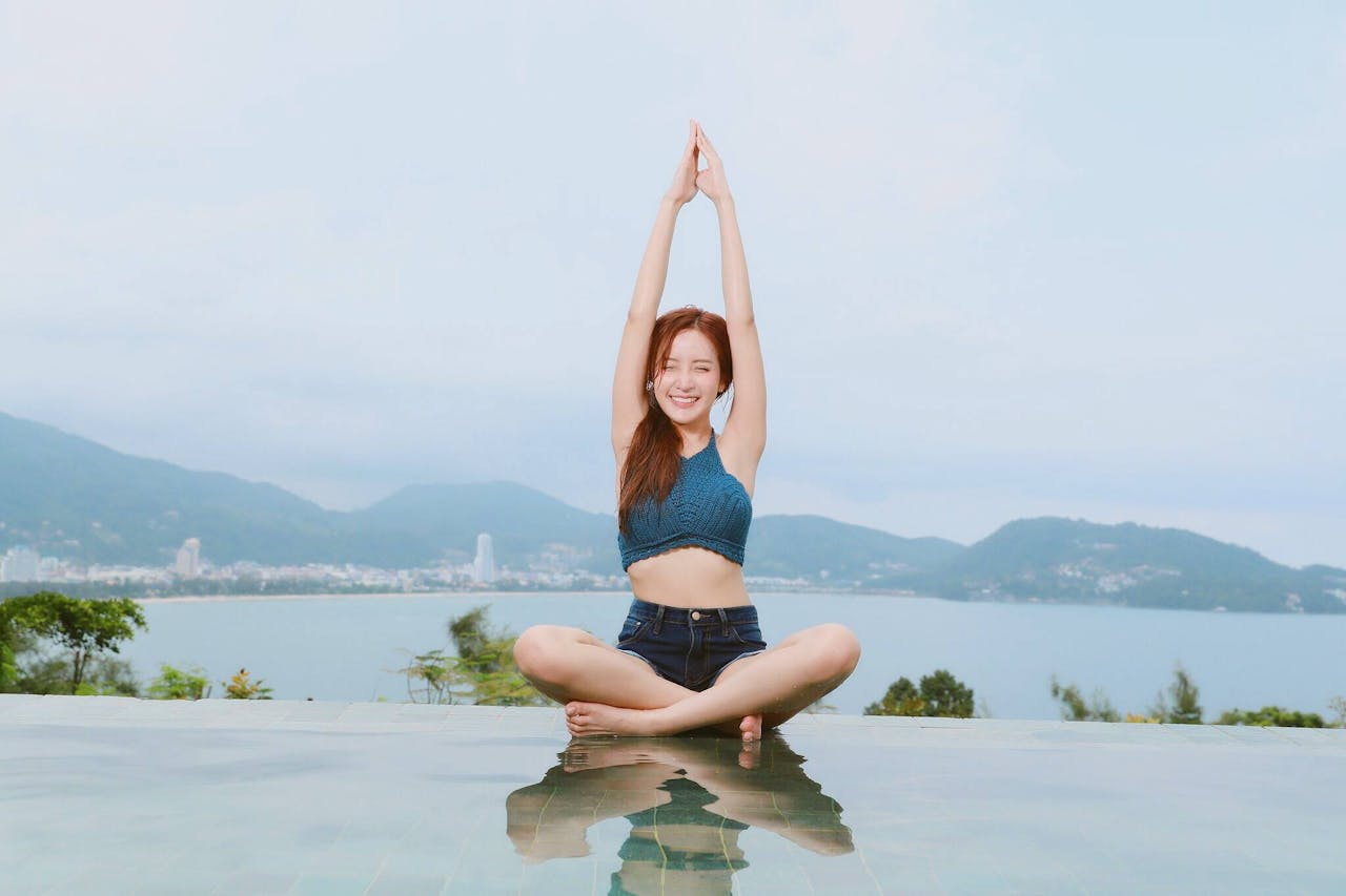 team-06 Young woman doing yoga by a scenic waterfront, enjoying a serene landscape.