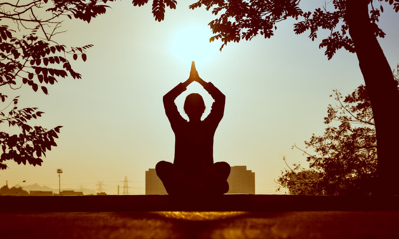 services-01 Silhouette of a person practicing yoga outdoors during sunrise, creating a calming atmosphere.