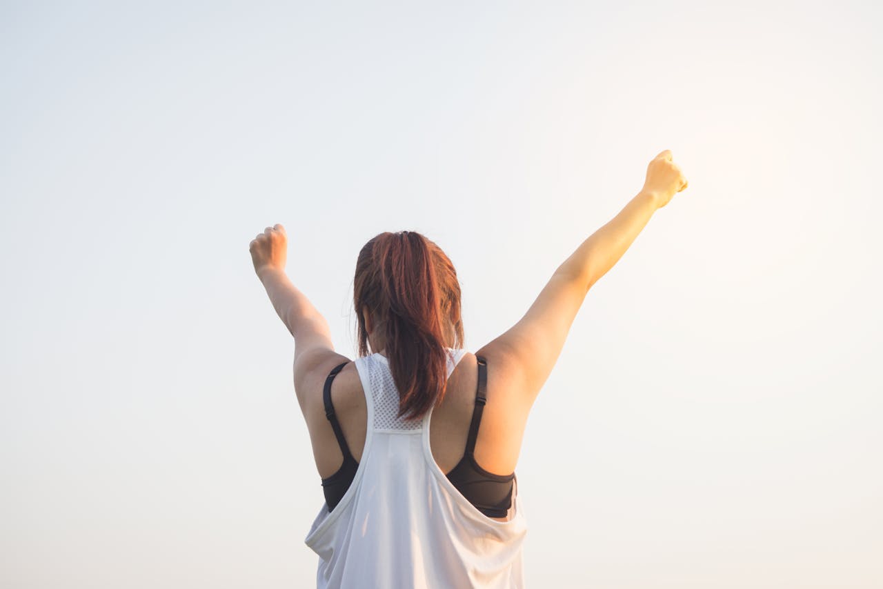 home-hero A woman celebrates success with arms raised in a bright outdoor setting.