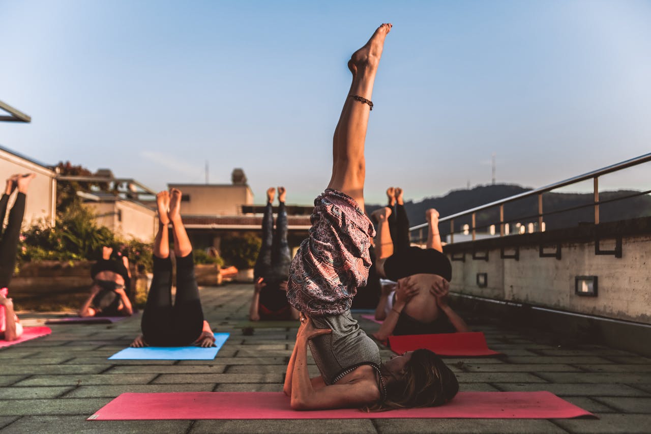 team-02 People practicing yoga on mats outdoors during sunset, focusing on wellness.