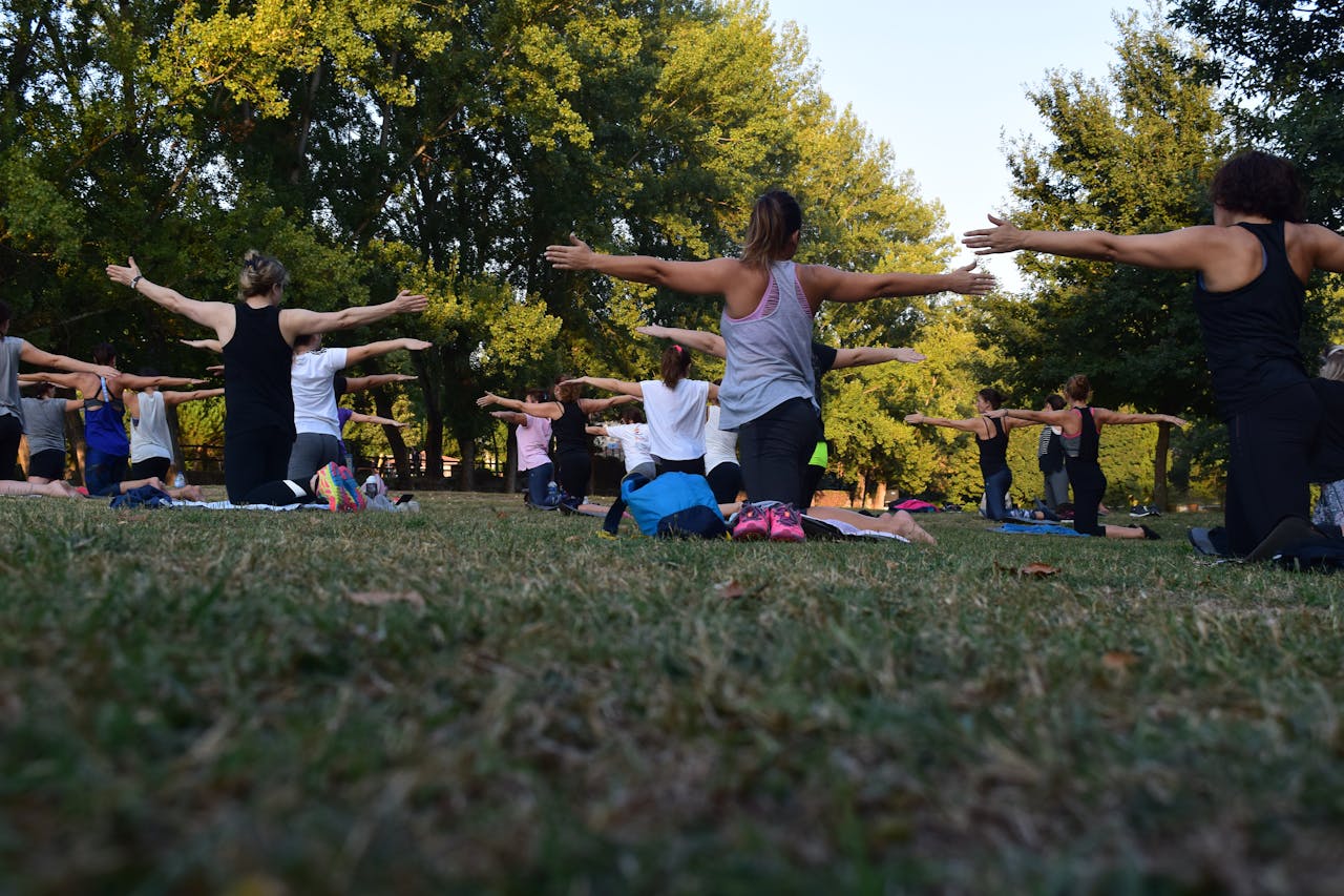 services-04 Group of adults practicing yoga outdoors in a park surrounded by trees.